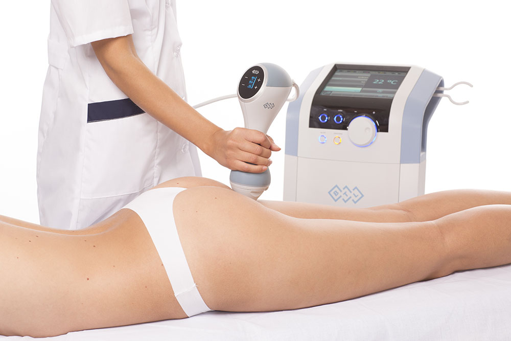 Practitioner treating a woman's thighs with a handheld device at our Chelsea clinic, EMtone cellulite reduction London